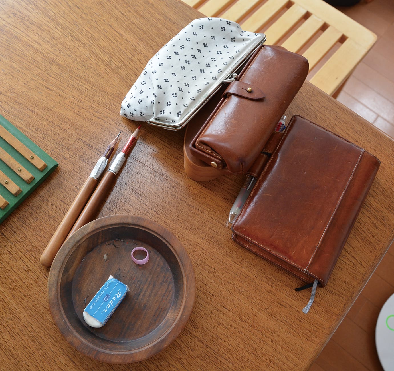 作業テーブルには木の鉛筆ホルダーや使い込まれた飴色の革の小物が並ぶ。
